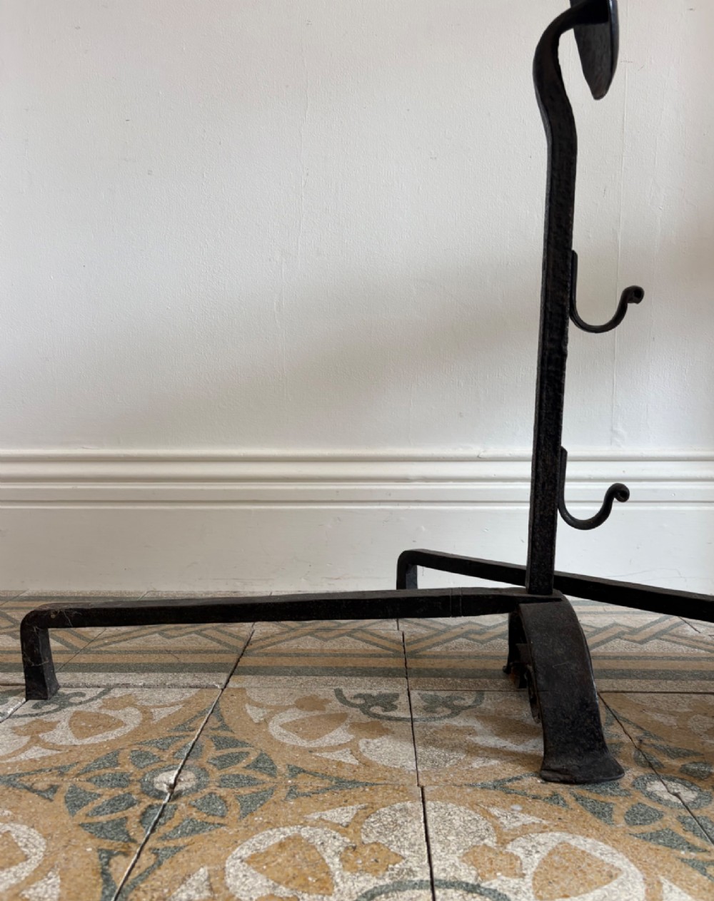 A pair of hand-forged black wrought iron fire dogs featuring circular disc tops, tool hooks, and scrolled arched feet. View VI