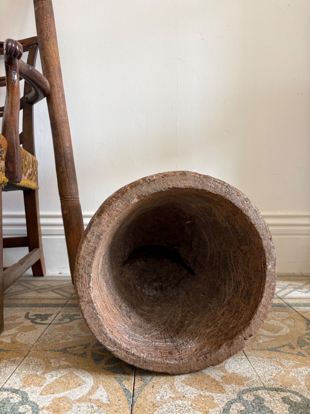 A hand-carved African hardwood grain mortar with side loop handles and concentric carved grooves, next to a tall wooden pestle pole. View VIII