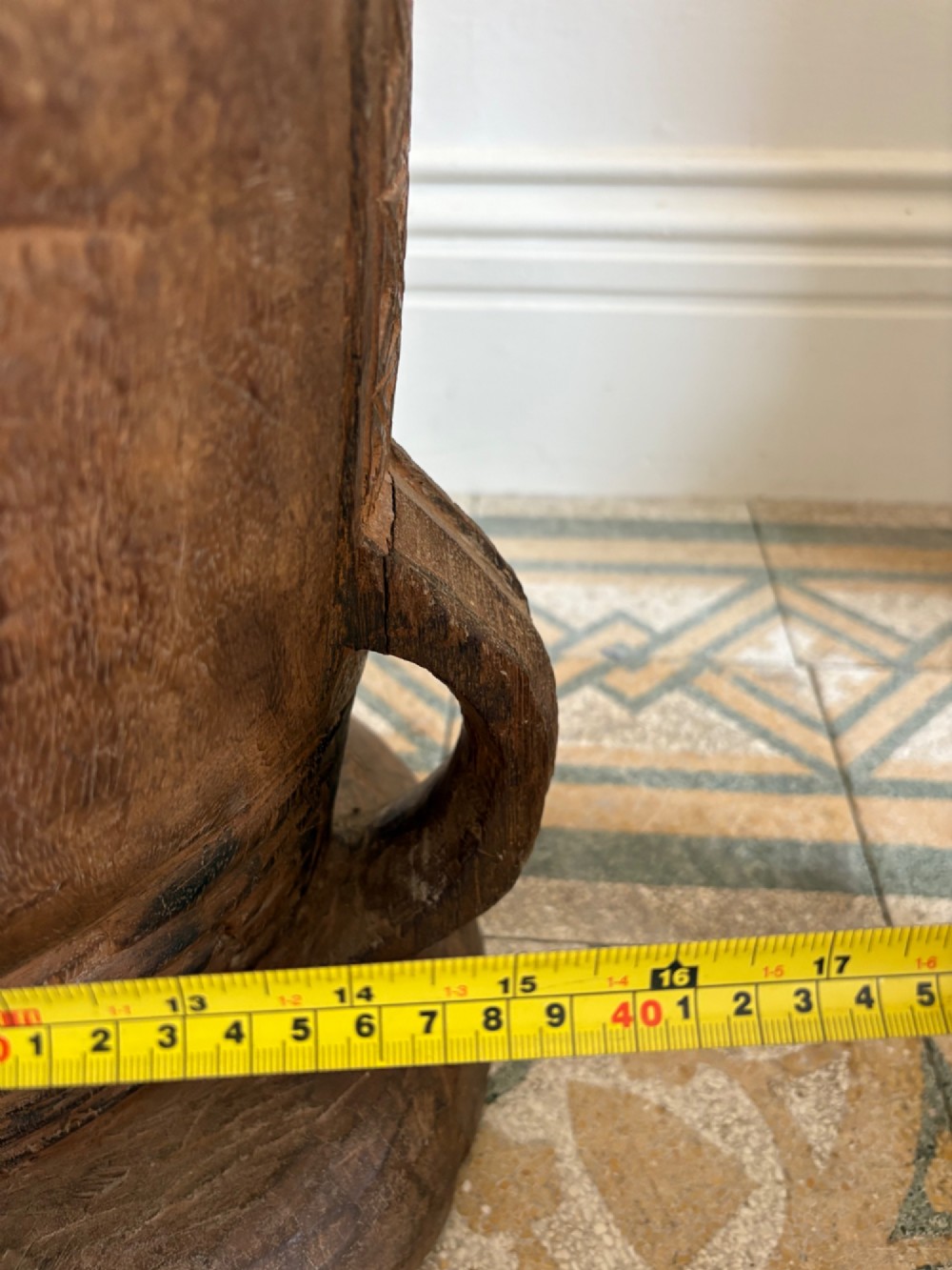 A hand-carved African hardwood grain mortar with side loop handles and concentric carved grooves, next to a tall wooden pestle pole. View XIII