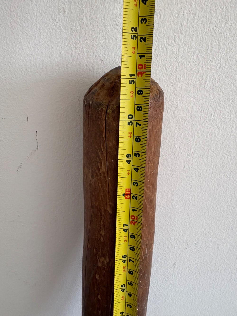 A hand-carved African hardwood grain mortar with side loop handles and concentric carved grooves, next to a tall wooden pestle pole. View XV