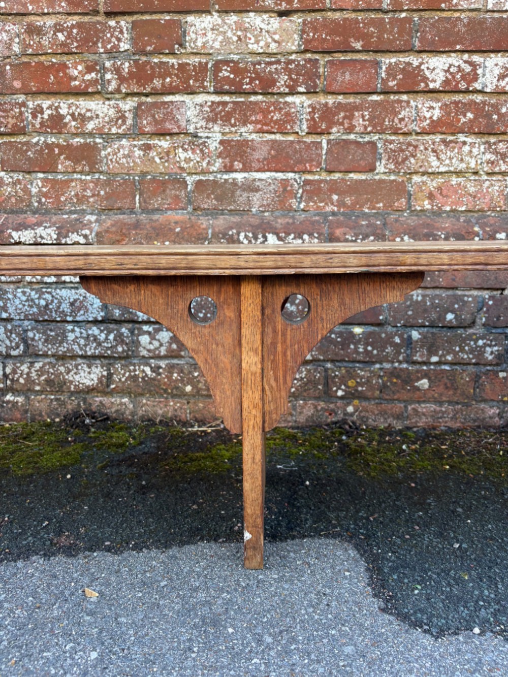 A long curved oak bench featuring trefoil carved cut-outs on the end supports. View IV