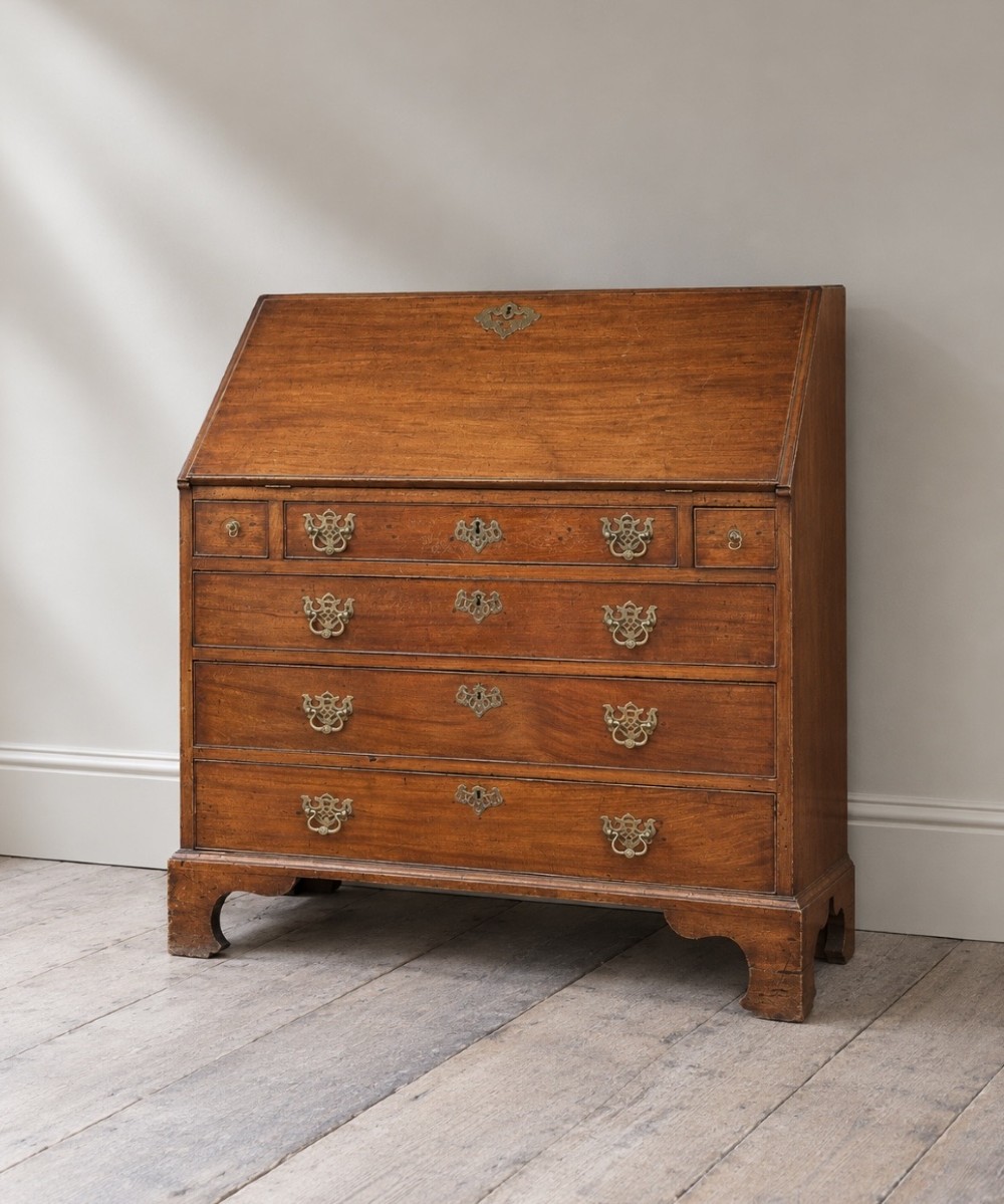 An 18th-century Georgian mahogany slant-front bureau shown open, featuring a fitted interior with small drawers and pigeonholes above three long drawers with brass handles, resting on bracket feet. View III