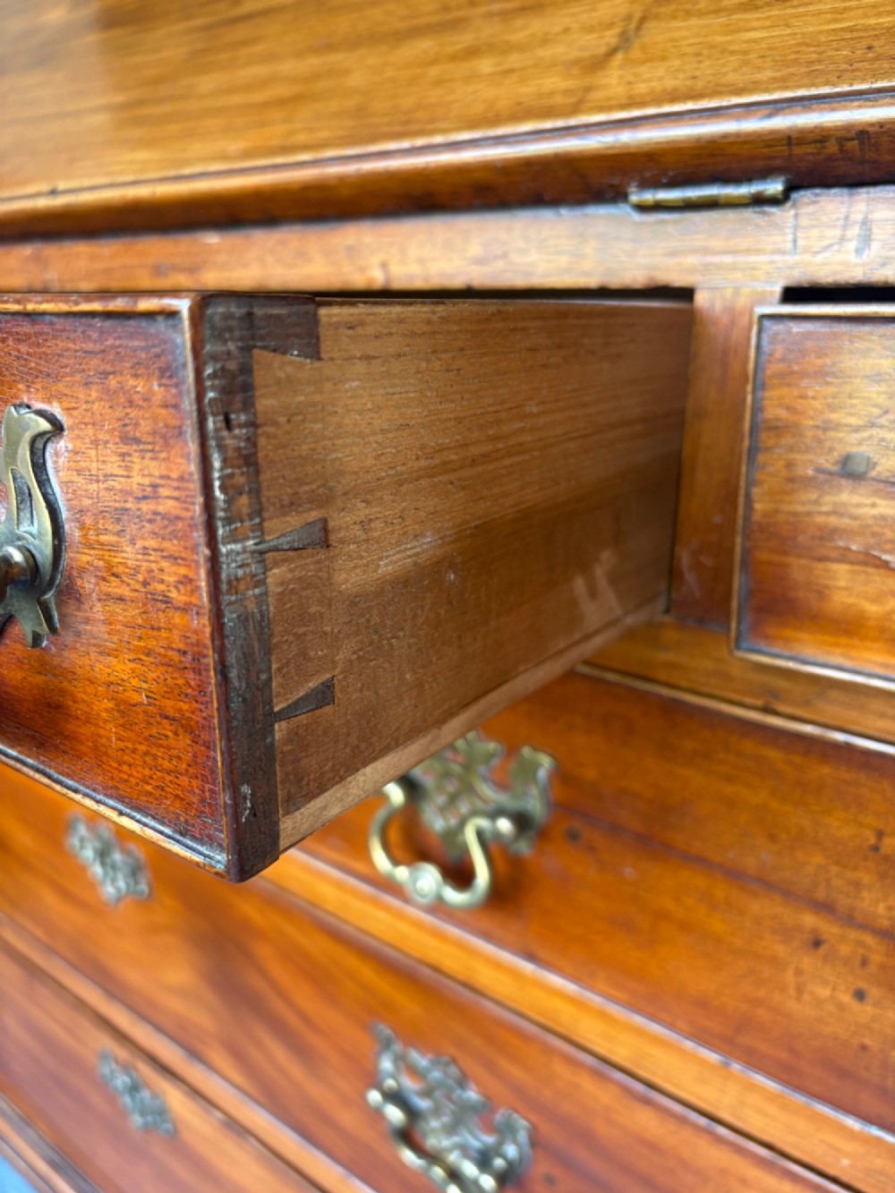 An 18th-century Georgian mahogany slant-front bureau shown open, featuring a fitted interior with small drawers and pigeonholes above three long drawers with brass handles, resting on bracket feet. View VI