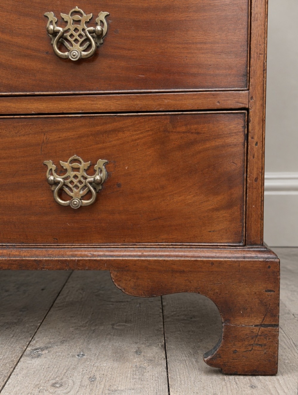 An 18th-century Georgian mahogany slant-front bureau shown open, featuring a fitted interior with small drawers and pigeonholes above three long drawers with brass handles, resting on bracket feet. View VII