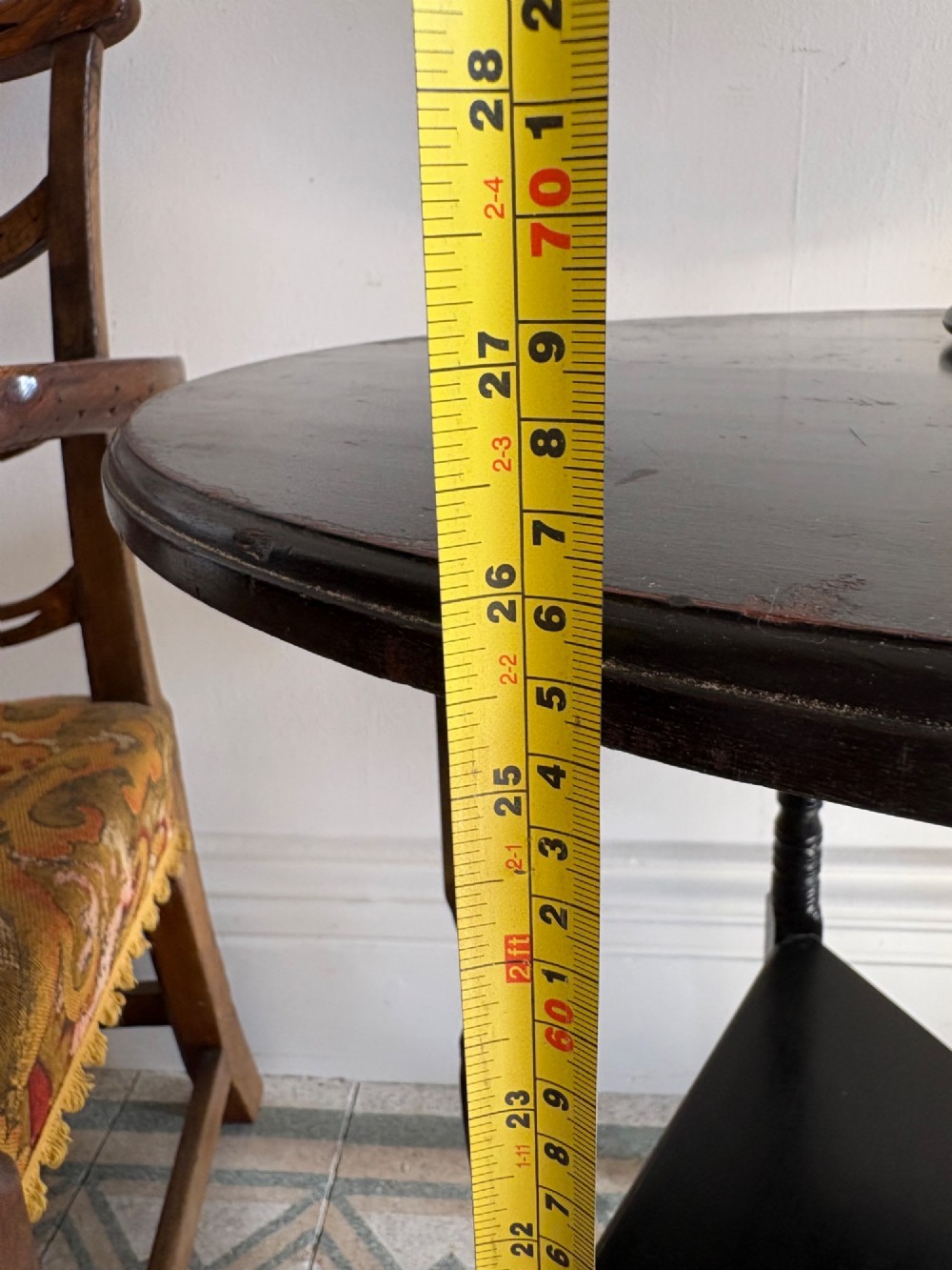 A late 19th-century ebonised round side table featuring three turned legs, slender splayed feet, and a lower triangular shelf bounded by a spindled gallery. View XIV