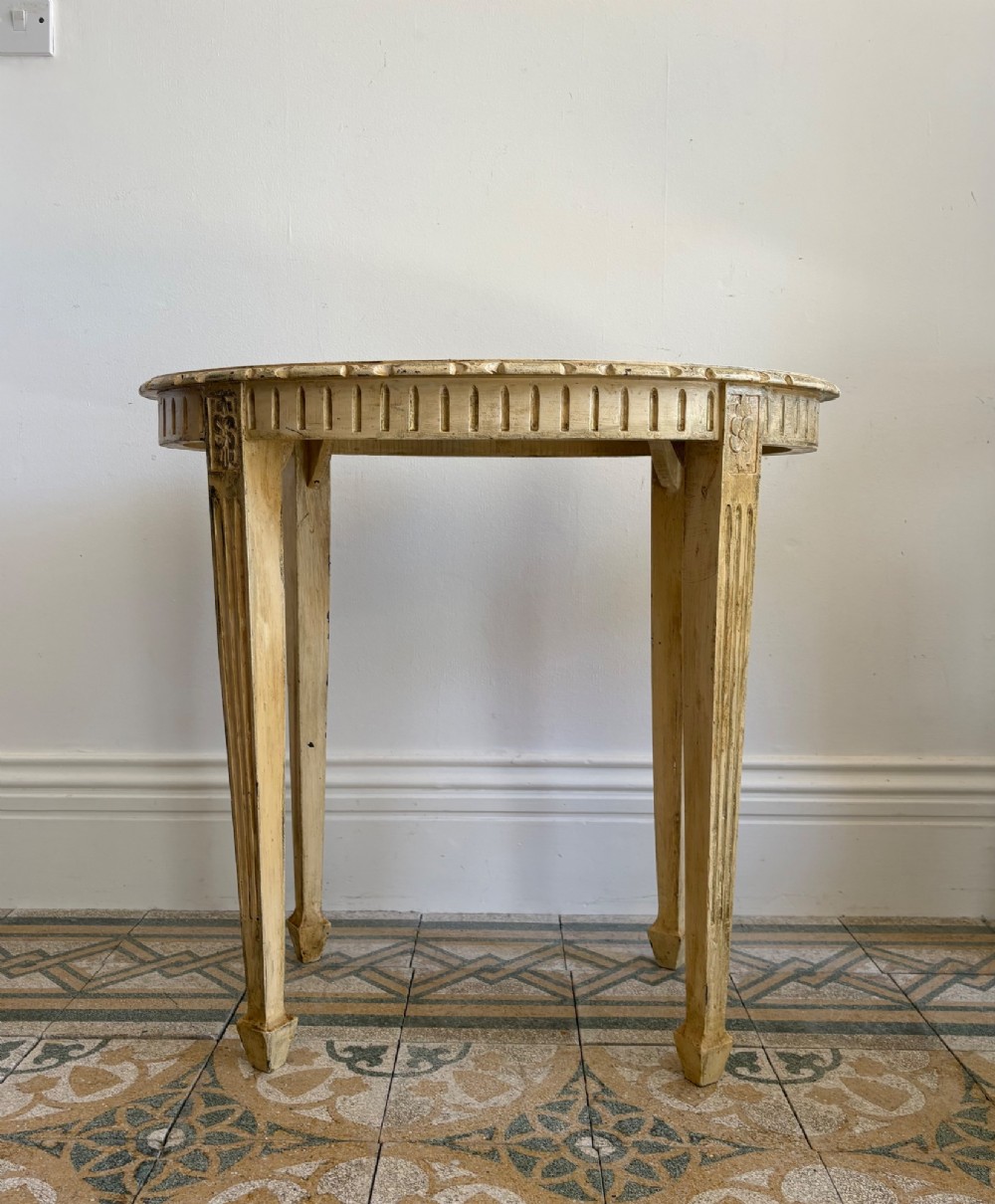 An oval cream-painted mahogany occasional table with hand-painted floral garlands, fluted apron, and square tapered fluted legs. View IV