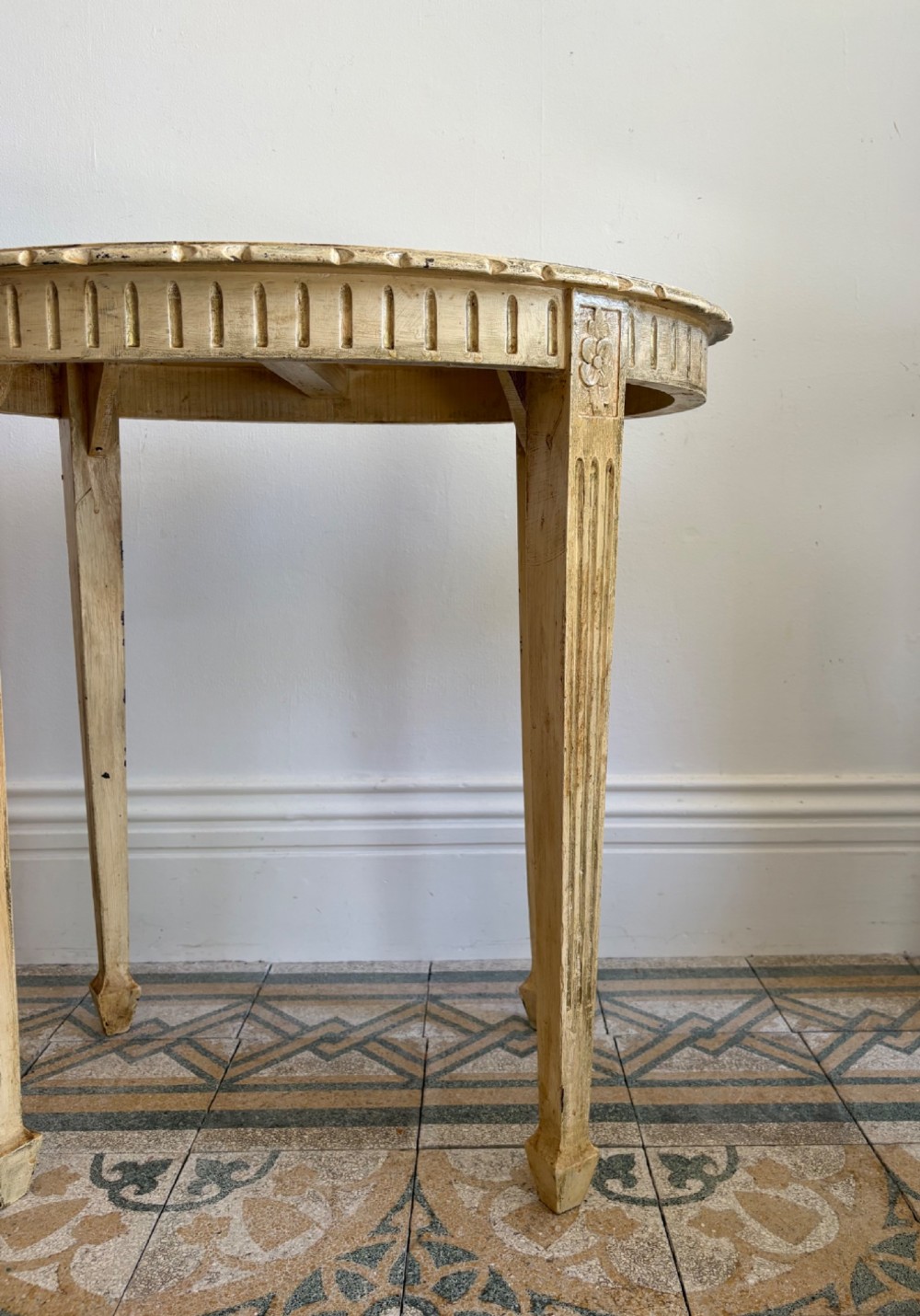 An oval cream-painted mahogany occasional table with hand-painted floral garlands, fluted apron, and square tapered fluted legs. View VI