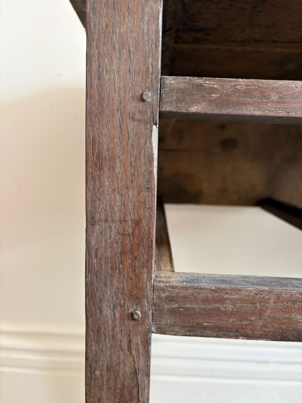 An early eighteenth-century oak lowboy side table featuring one wide upper drawer, two small side drawers, an arched apron, brass handles, and straight square legs. View XII