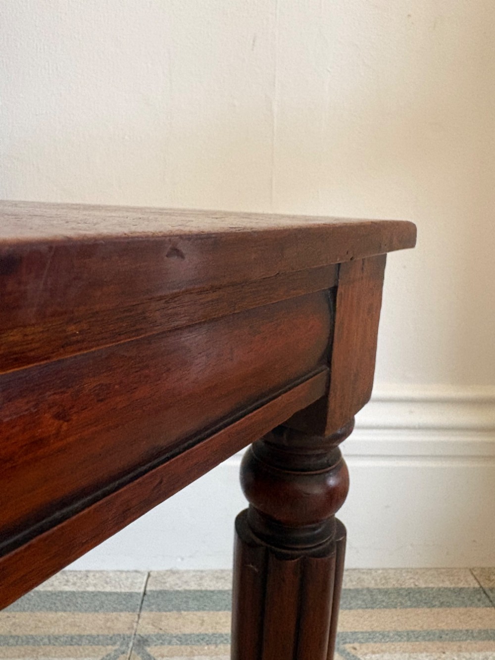 An antique William IV mahogany hall chair featuring a carved crest backrest, solid flat seat, and fluted turned front legs. View V