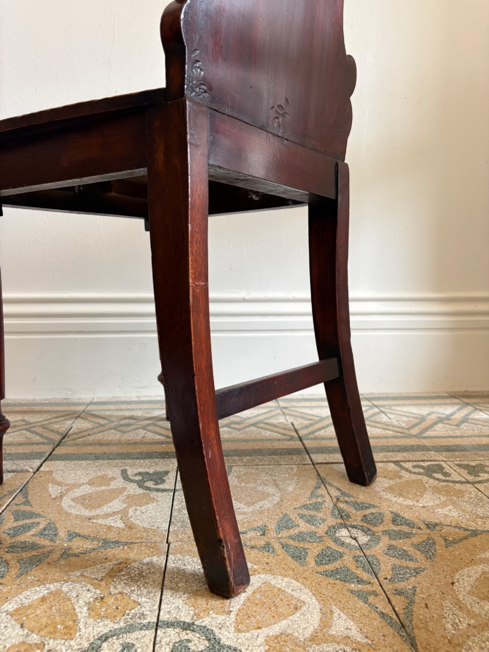 An antique William IV mahogany hall chair featuring a carved crest backrest, solid flat seat, and fluted turned front legs. View IX