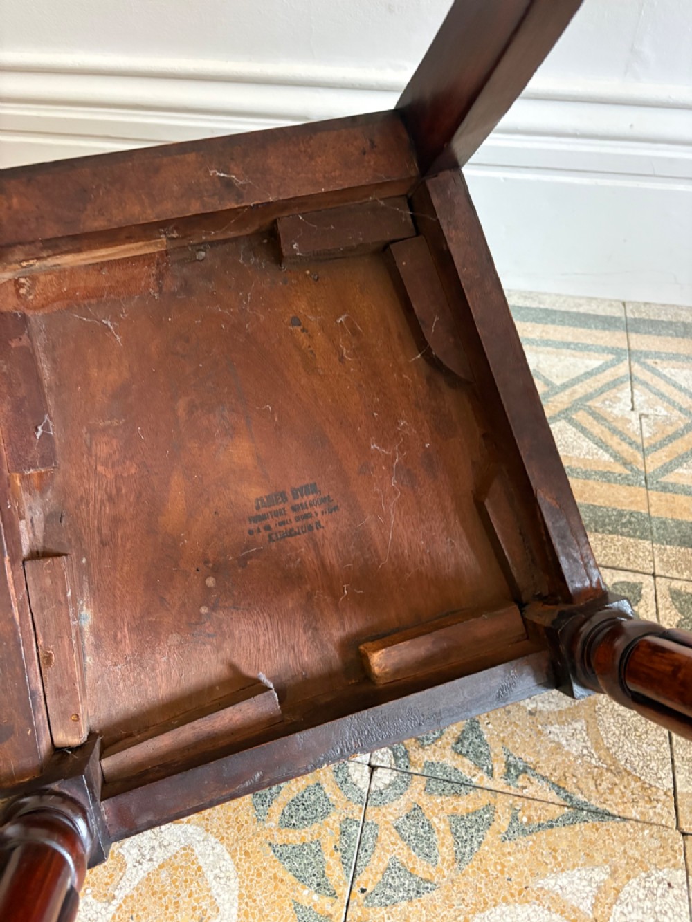 An antique William IV mahogany hall chair featuring a carved crest backrest, solid flat seat, and fluted turned front legs. View X