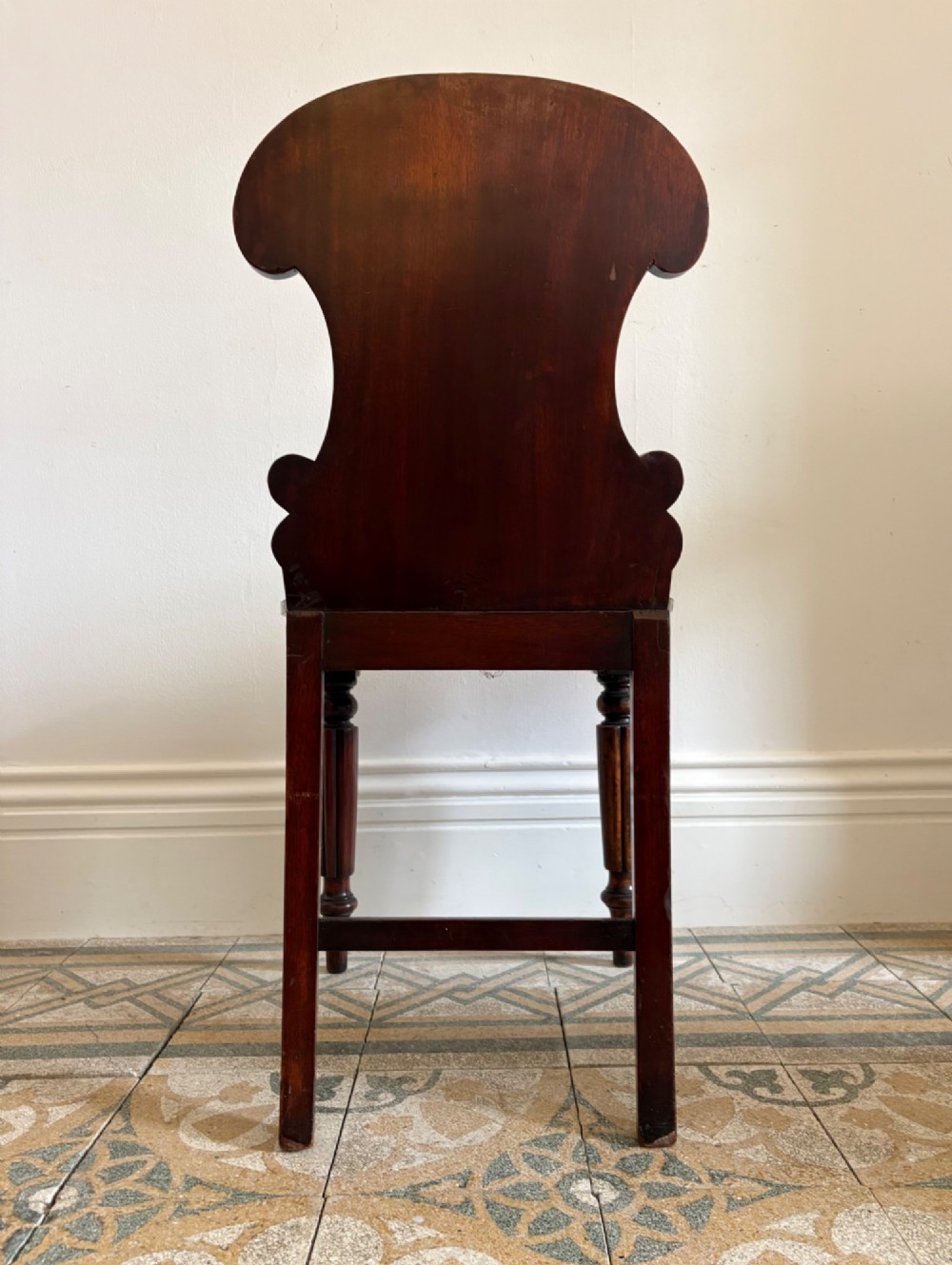 An antique William IV mahogany hall chair featuring a carved crest backrest, solid flat seat, and fluted turned front legs. View XI