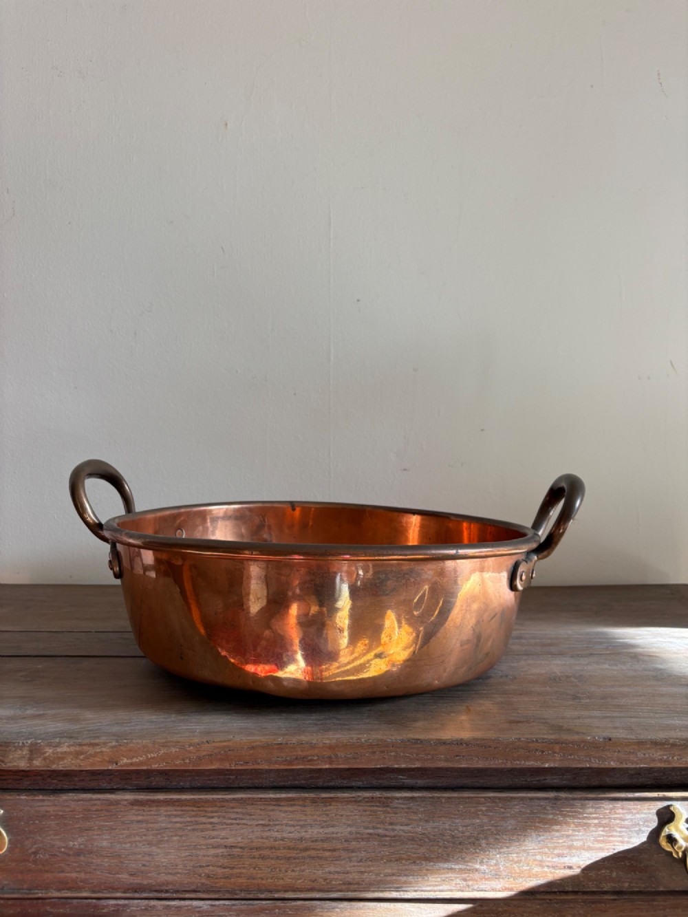 A large 19th-century polished copper preserve pan featuring twin riveted brass handles. View II