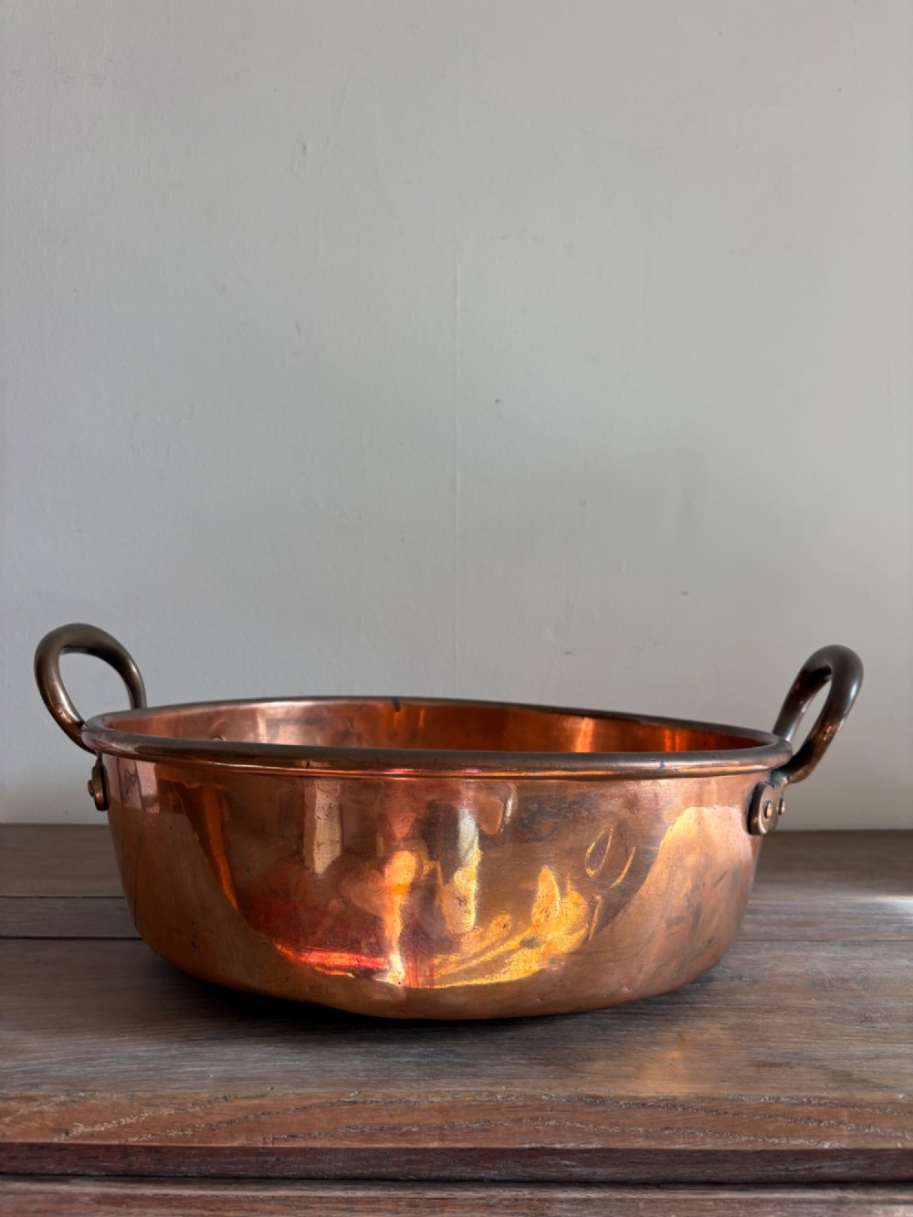 A large 19th-century polished copper preserve pan featuring twin riveted brass handles. View III