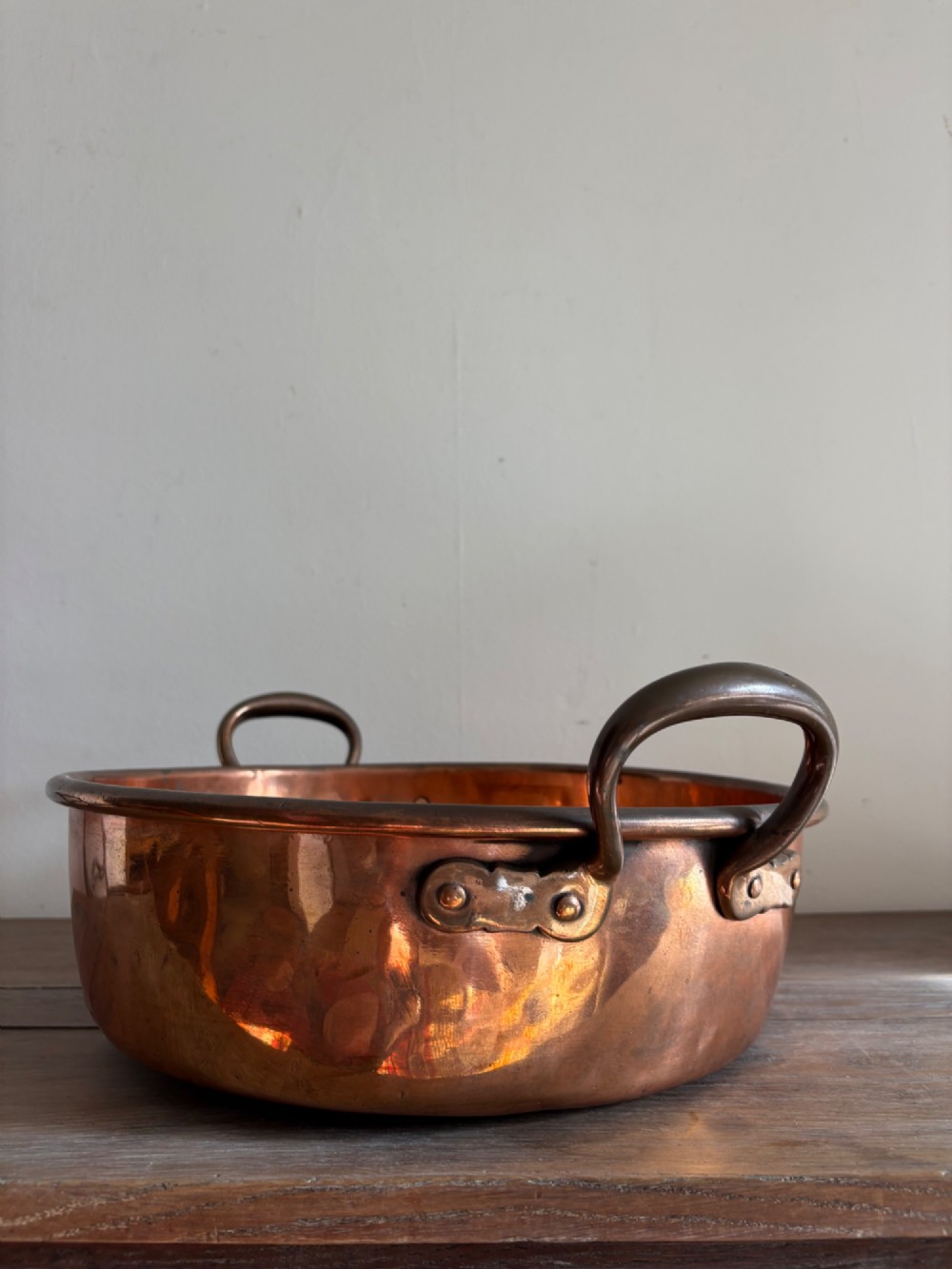 A large 19th-century polished copper preserve pan featuring twin riveted brass handles. View IV