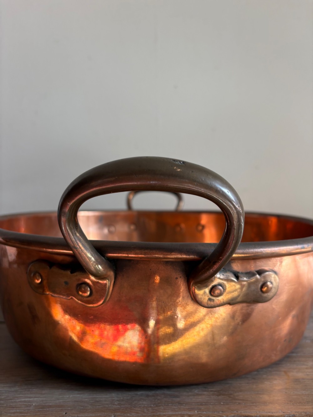 A large 19th-century polished copper preserve pan featuring twin riveted brass handles. View V