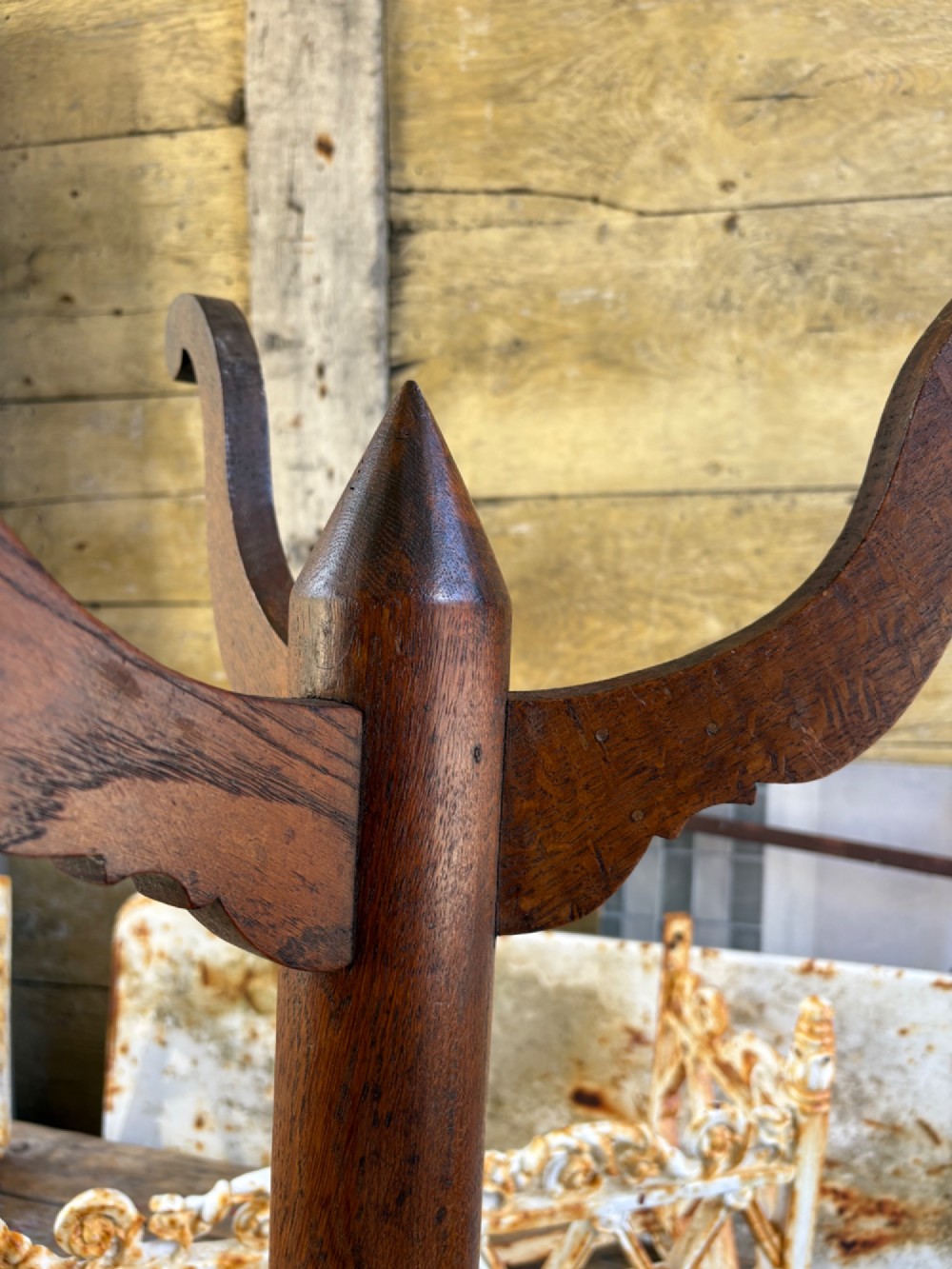 An English Arts and Crafts solid oak wine table featuring a circular top, an under-top support bracket, a central column terminating in a pointed lower finial, and three splayed cabriole legs. View III