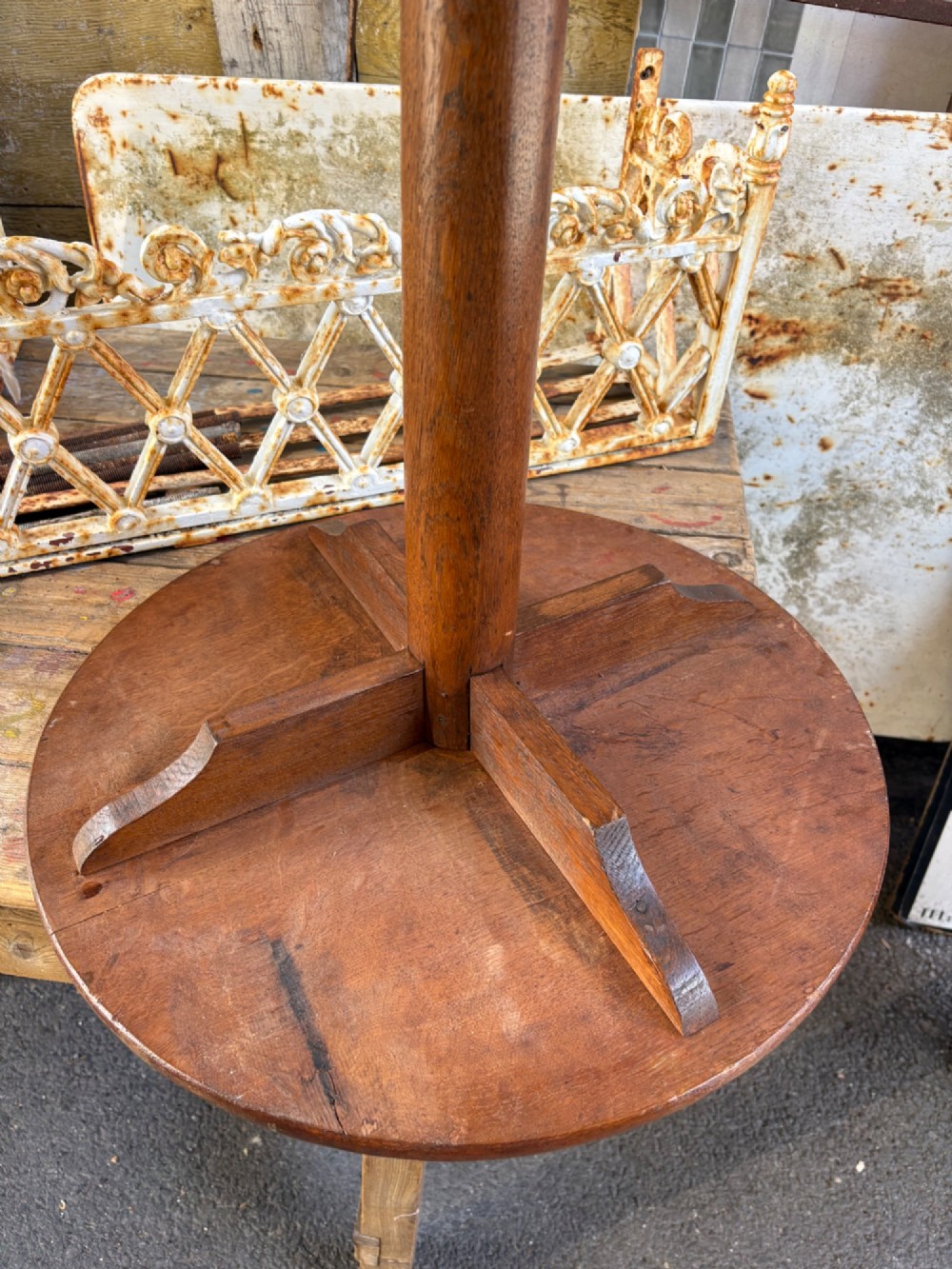 An English Arts and Crafts solid oak wine table featuring a circular top, an under-top support bracket, a central column terminating in a pointed lower finial, and three splayed cabriole legs. View IV