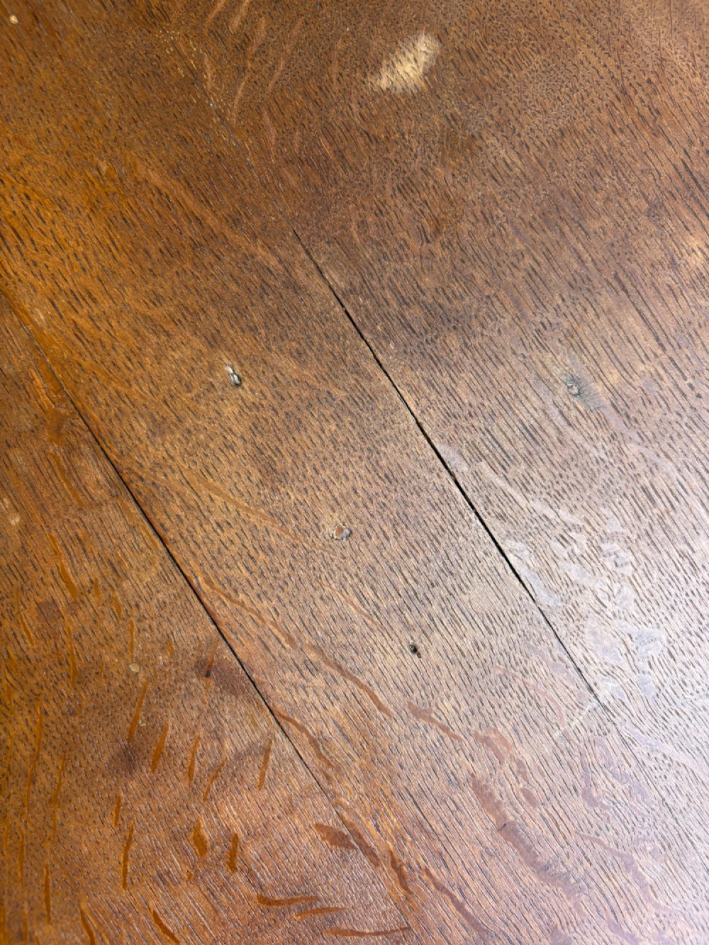 An English Arts and Crafts solid oak wine table featuring a circular top, an under-top support bracket, a central column terminating in a pointed lower finial, and three splayed cabriole legs. View VI