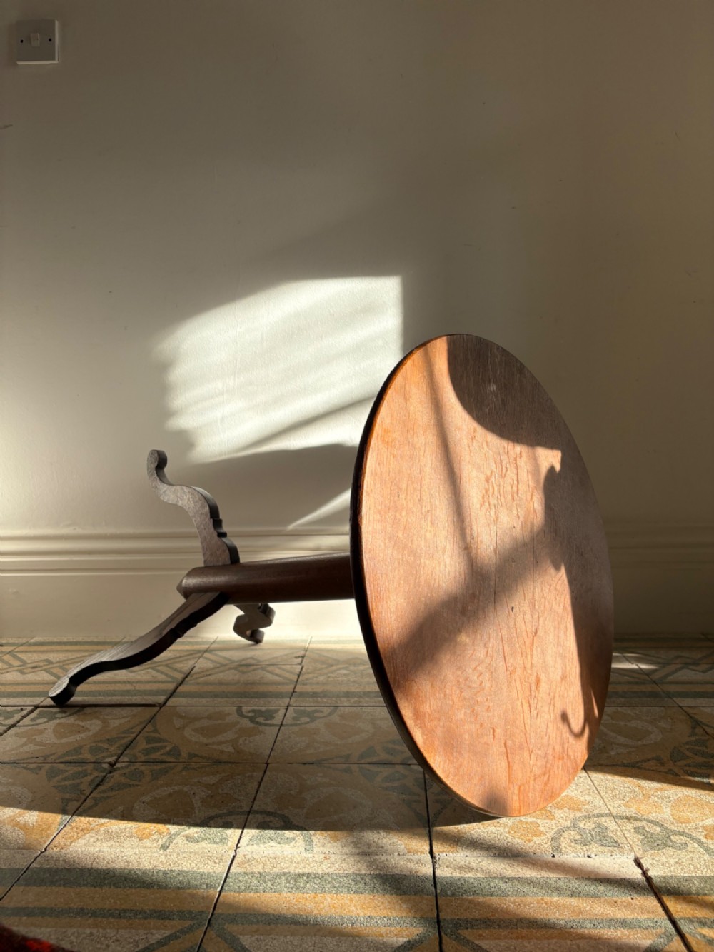 An English Arts and Crafts solid oak wine table featuring a circular top, an under-top support bracket, a central column terminating in a pointed lower finial, and three splayed cabriole legs. View X