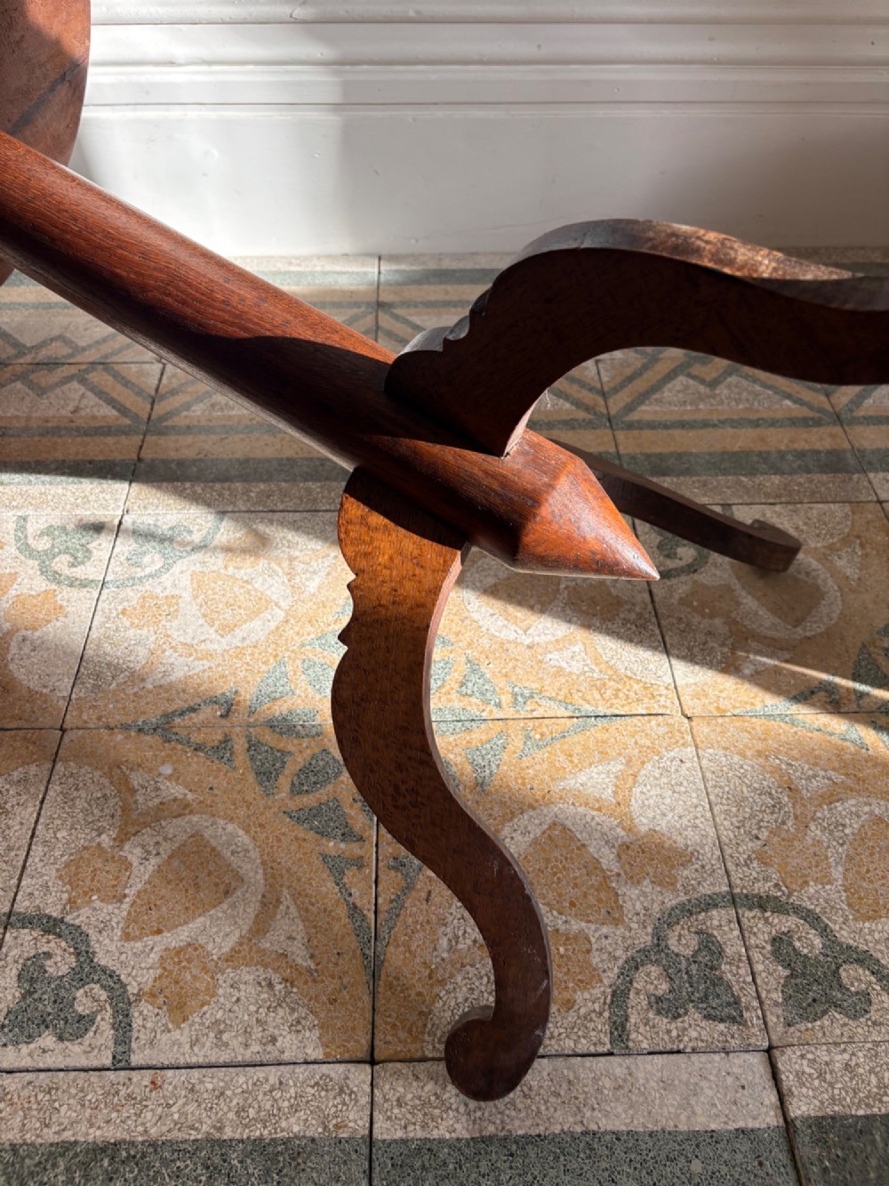 An English Arts and Crafts solid oak wine table featuring a circular top, an under-top support bracket, a central column terminating in a pointed lower finial, and three splayed cabriole legs. View XII