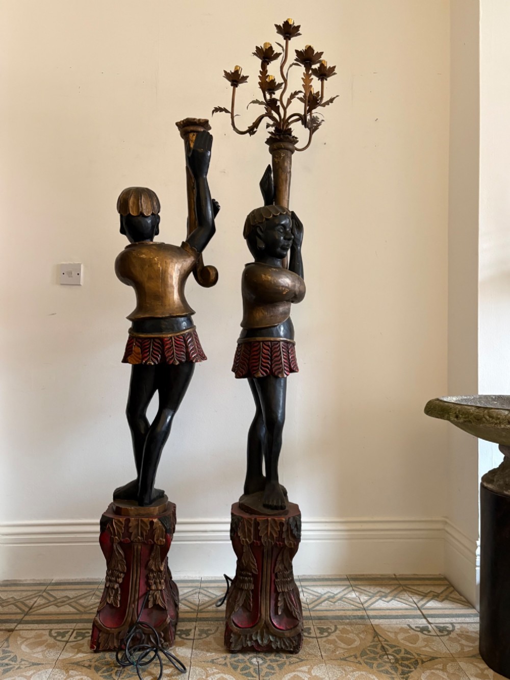 A pair of life-sized Venetian carved wood figure floor lamps featuring gilt and polychrome details, mounted on ornate pedestals with multi-light metal candelabra tops. View II