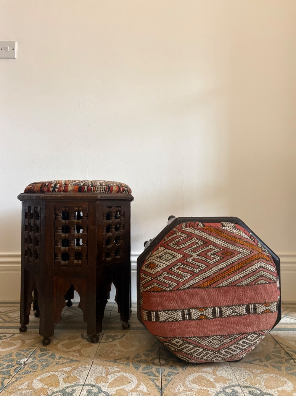 A pair of dark wood octagonal stools with turned latticework side panels, arch-cut bases, and geometric woven kilim seat cushions. View III