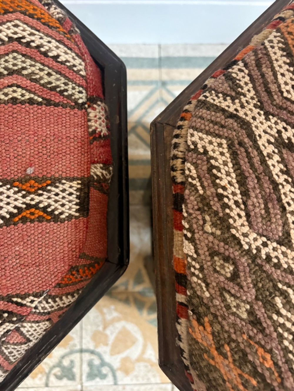 A pair of dark wood octagonal stools with turned latticework side panels, arch-cut bases, and geometric woven kilim seat cushions. View VII