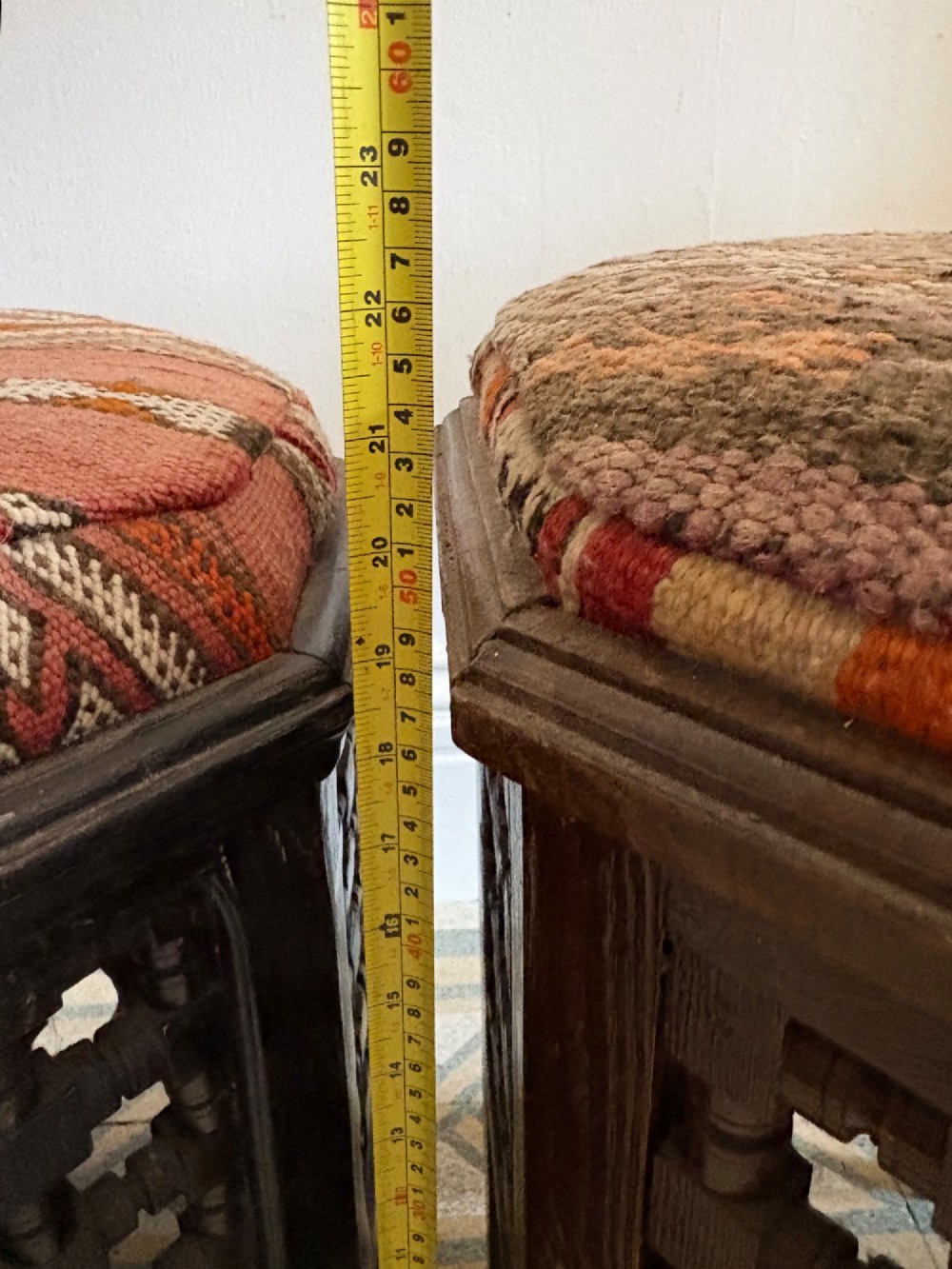 A pair of dark wood octagonal stools with turned latticework side panels, arch-cut bases, and geometric woven kilim seat cushions. View X