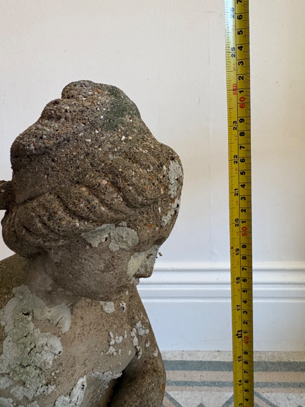 A weathered cast stone statue depicting a seated classical female bather figure with a natural lichen patina. View XIII