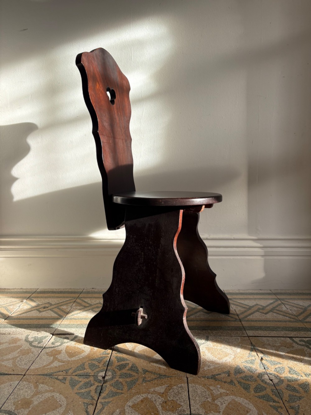 An Arts and Crafts dark mahogany hall chair featuring a shaped backrest with a pierced heart cutout and splayed legs. View II