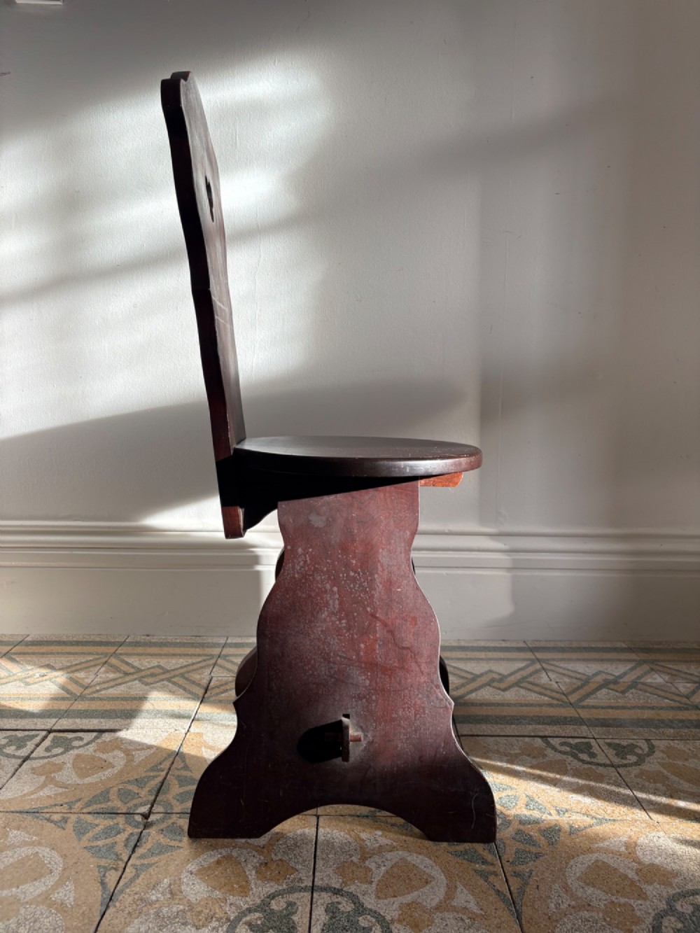 An Arts and Crafts dark mahogany hall chair featuring a shaped backrest with a pierced heart cutout and splayed legs. View III
