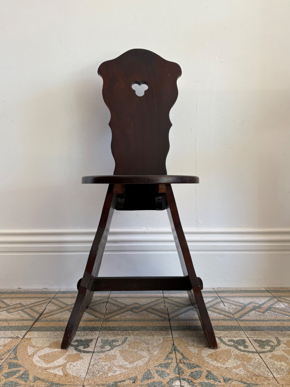 An Arts and Crafts dark mahogany hall chair featuring a shaped backrest with a pierced heart cutout and splayed legs. View V