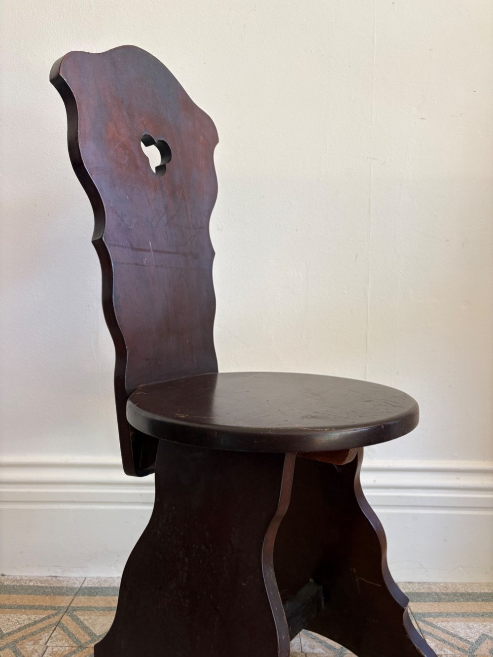 An Arts and Crafts dark mahogany hall chair featuring a shaped backrest with a pierced heart cutout and splayed legs. View VIII