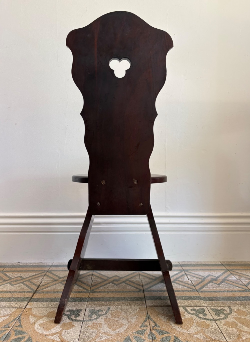 An Arts and Crafts dark mahogany hall chair featuring a shaped backrest with a pierced heart cutout and splayed legs. View IX
