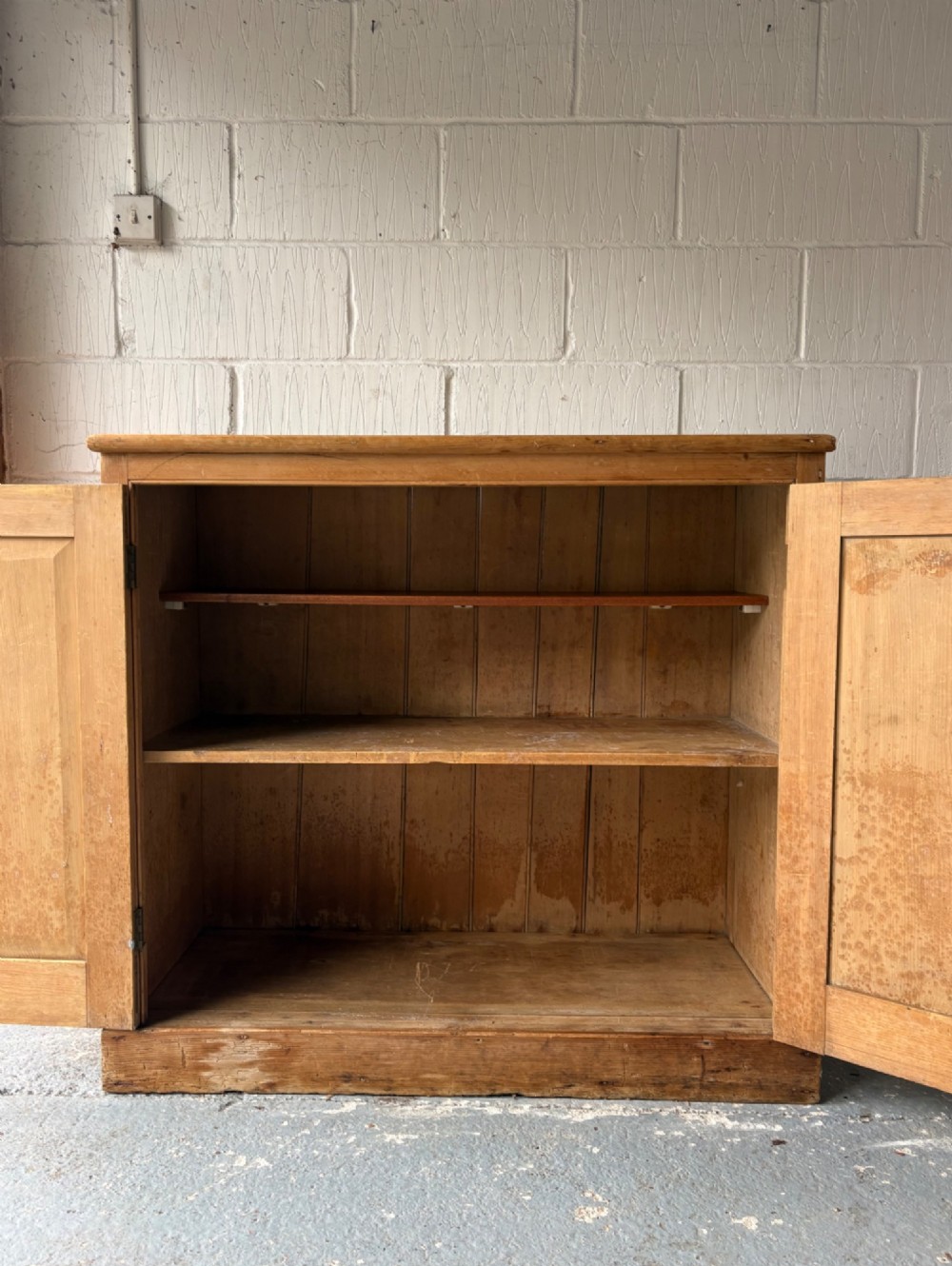 A nineteenth-century Victorian pine two-door cupboard featuring recessed panel doors, brass knobs, and a solid plinth base. View II