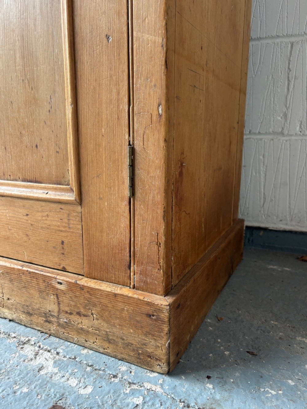 A nineteenth-century Victorian pine two-door cupboard featuring recessed panel doors, brass knobs, and a solid plinth base. View IV