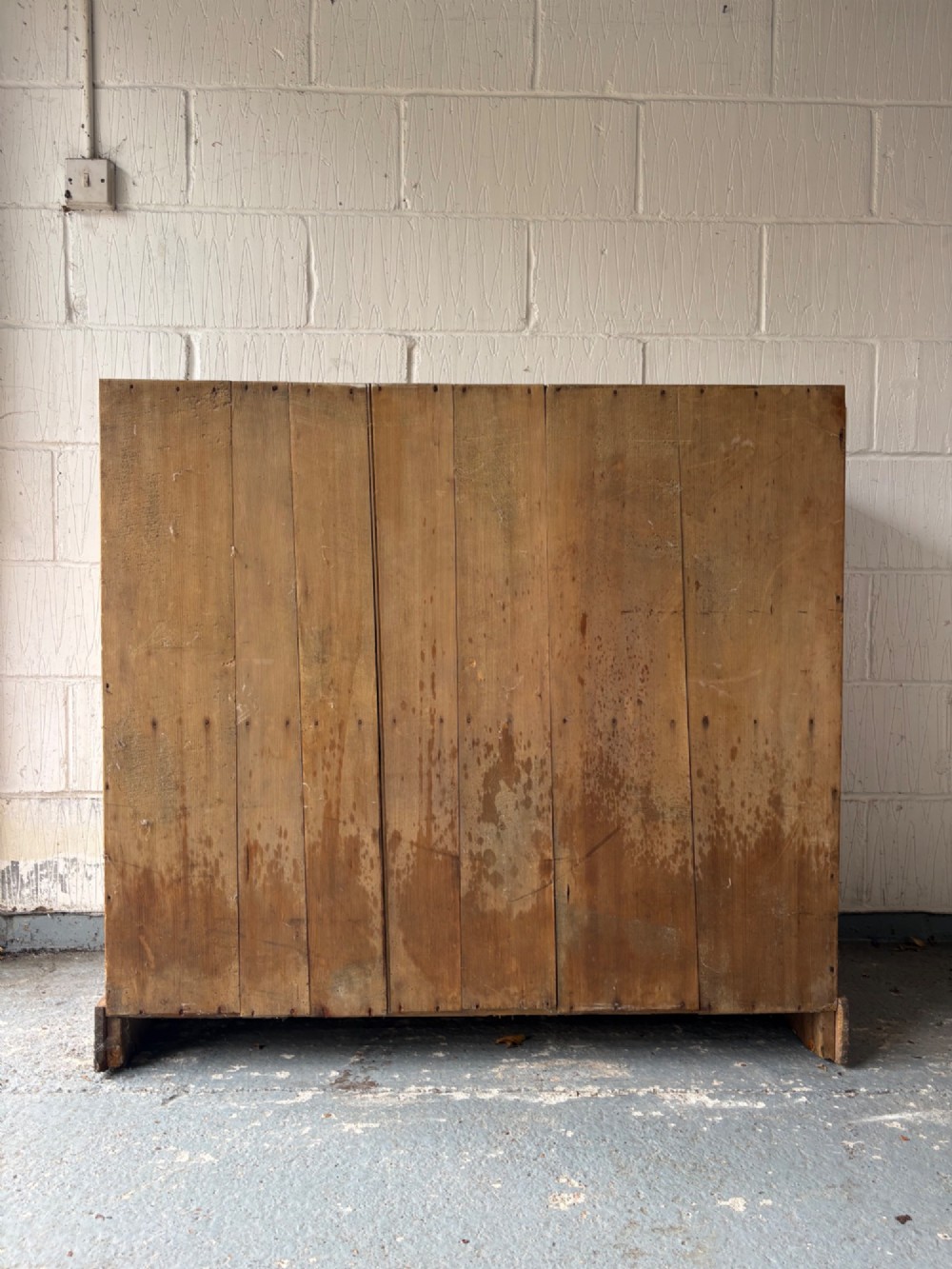 A nineteenth-century Victorian pine two-door cupboard featuring recessed panel doors, brass knobs, and a solid plinth base. View V