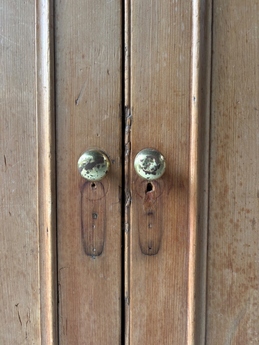 A nineteenth-century Victorian pine two-door cupboard featuring recessed panel doors, brass knobs, and a solid plinth base. View VI