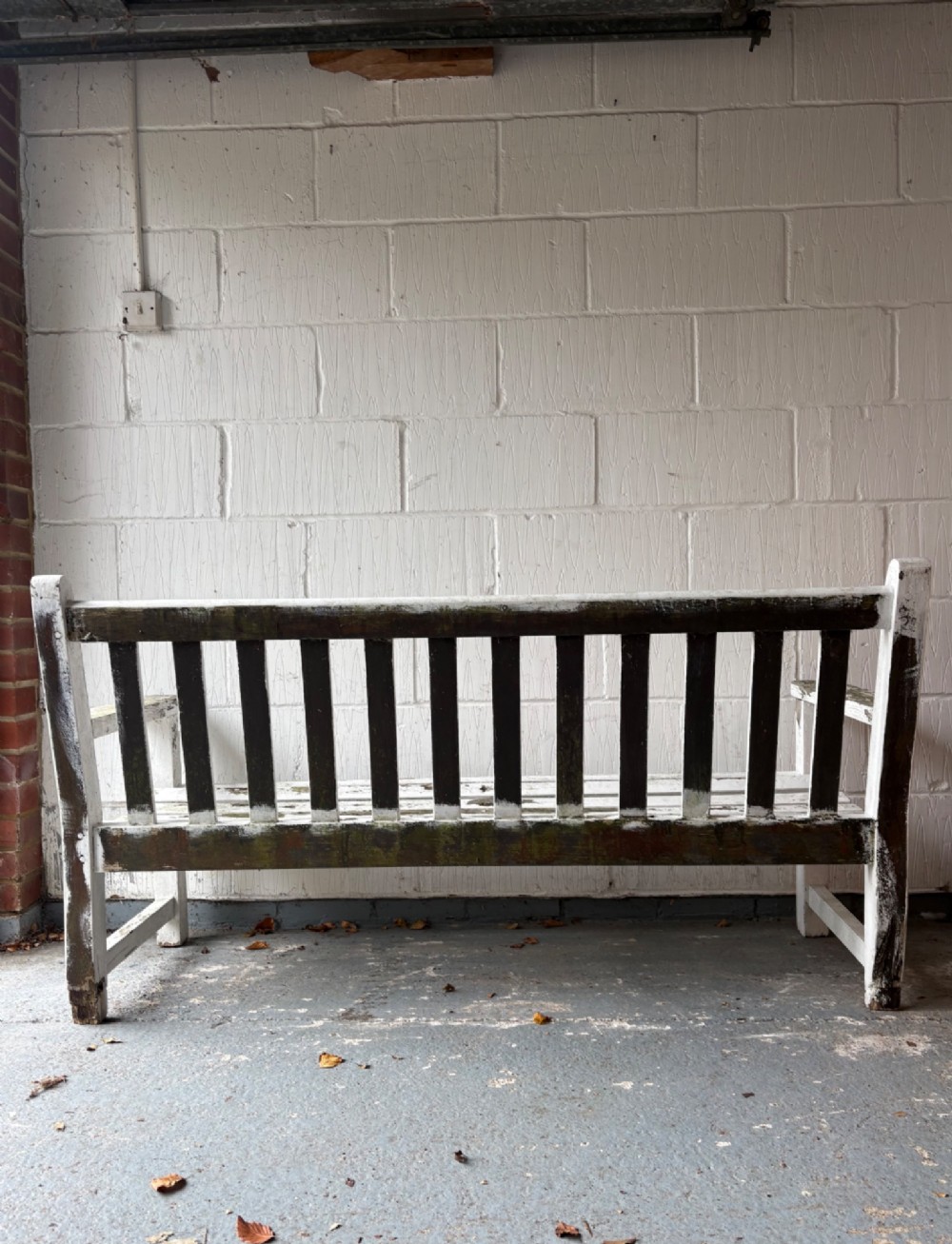 An early 20th-century teak garden bench with a vertical slatted backrest, flat armrests, and a weathered white painted finish. View IV