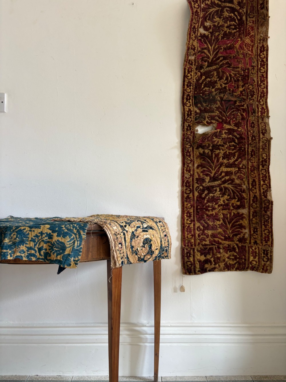 A long vertical 17th-century Italian crimson velvet textile fragment with gold silk acanthus leaf embroidery and patterned borders. View II