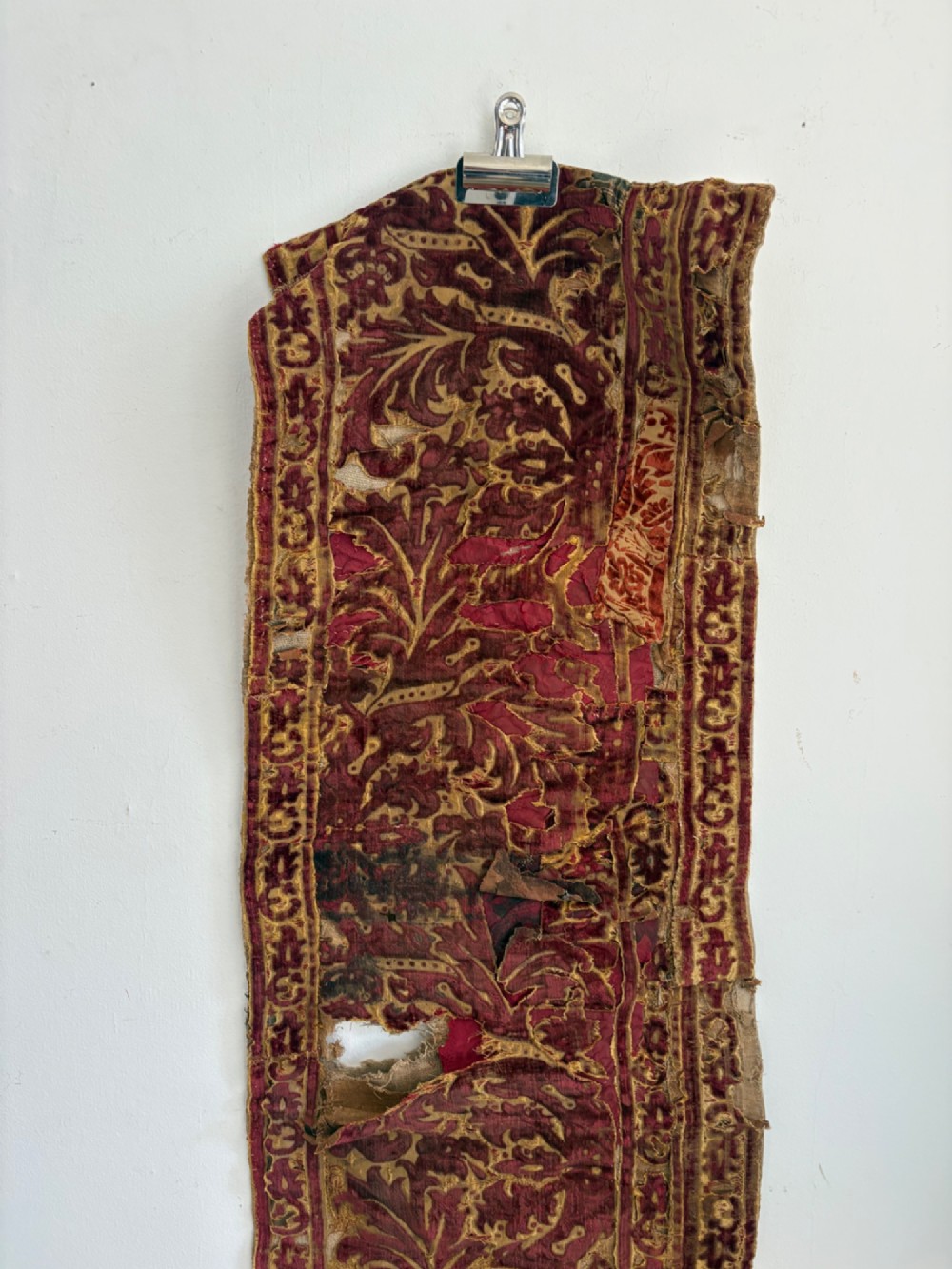 A long vertical 17th-century Italian crimson velvet textile fragment with gold silk acanthus leaf embroidery and patterned borders. View V