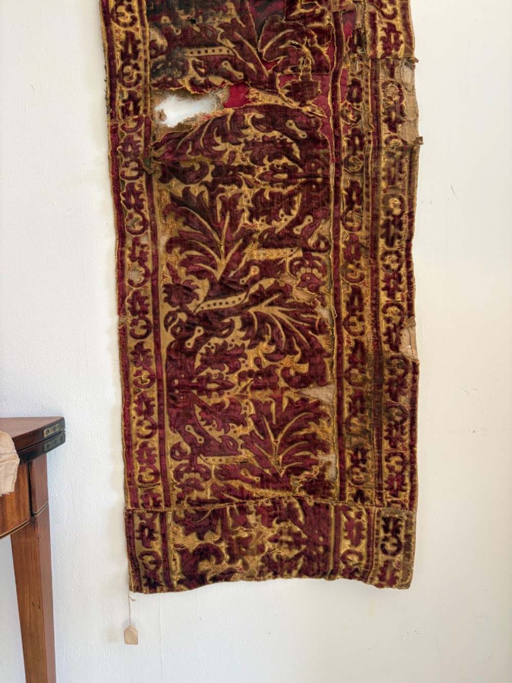 A long vertical 17th-century Italian crimson velvet textile fragment with gold silk acanthus leaf embroidery and patterned borders. View VI
