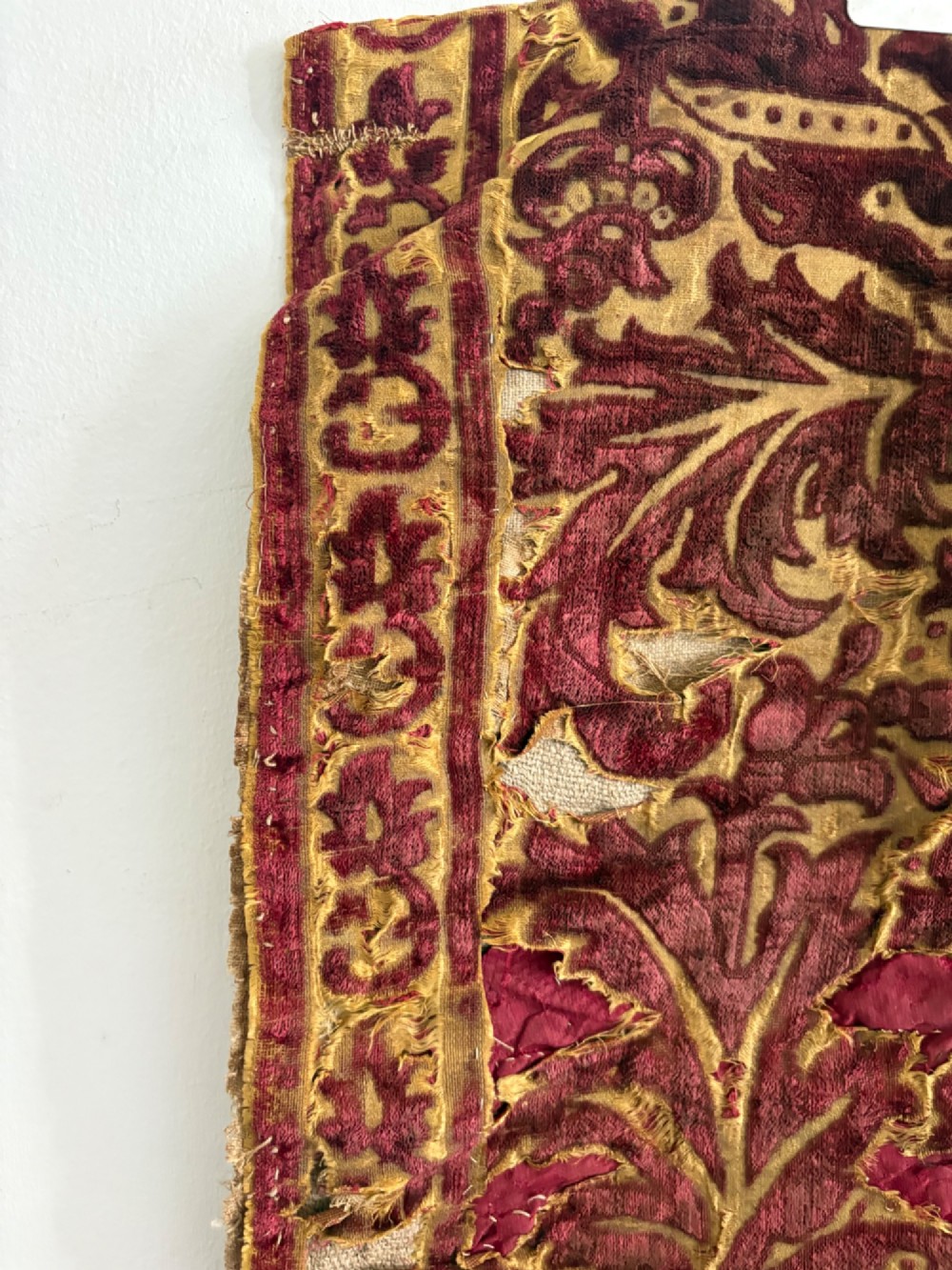 A long vertical 17th-century Italian crimson velvet textile fragment with gold silk acanthus leaf embroidery and patterned borders. View IX