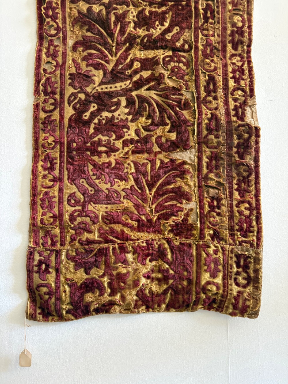 A long vertical 17th-century Italian crimson velvet textile fragment with gold silk acanthus leaf embroidery and patterned borders. View X