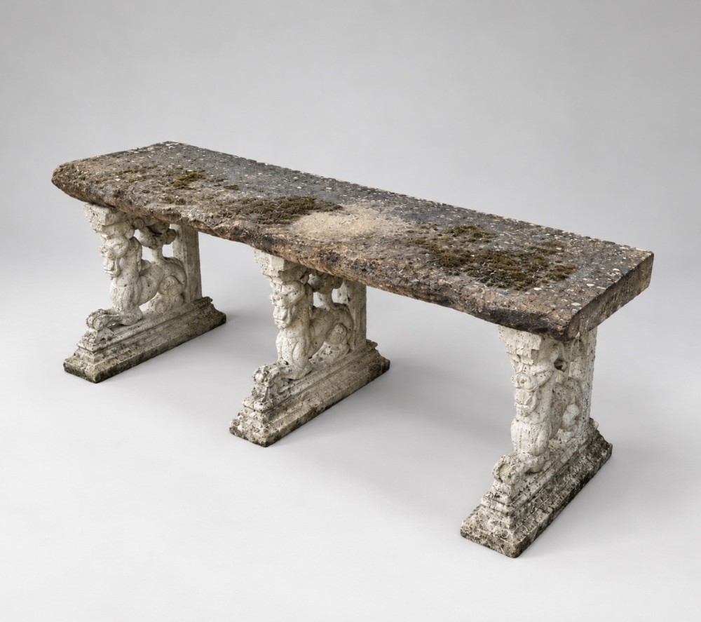 A weathered stone garden bench featuring a rectangular York stone top resting on three cast stone griffin pedestals. View II