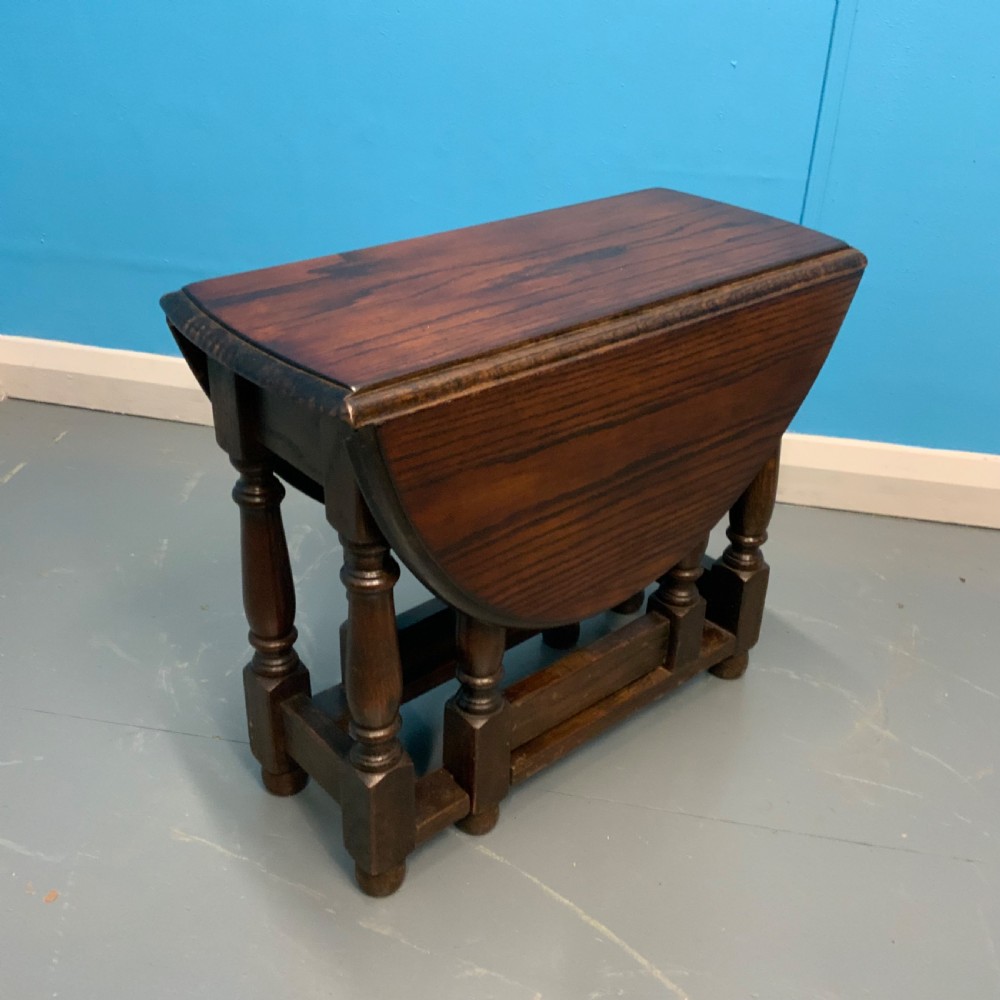 A dark oak gateleg side table featuring turned baluster legs, base stretchers, and hinged drop-leaf sides. View III