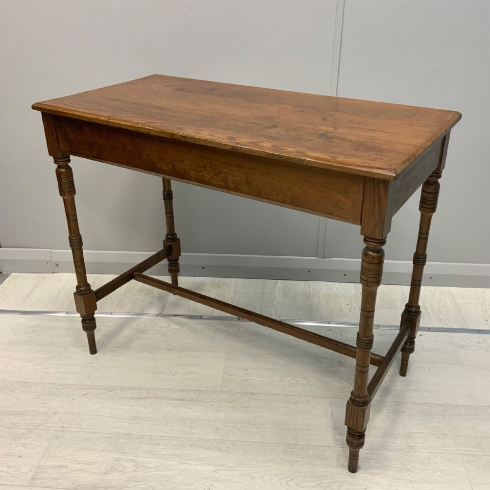 A nineteenth-century pitch pine side table featuring turned legs connected by a low stretcher base and a rectangular wooden top.