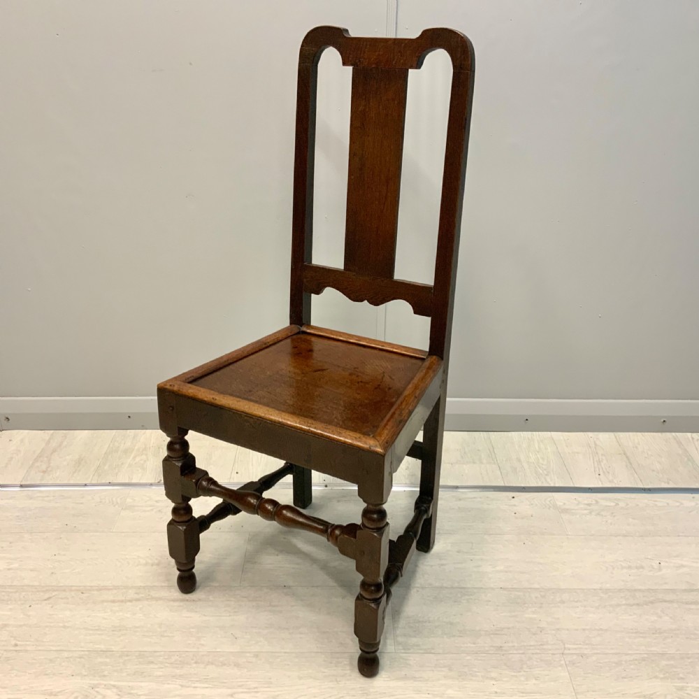 A late 17th-century dark oak back stool side chair featuring a solid wooden seat, central back splat, and turned front legs with stretchers. View III