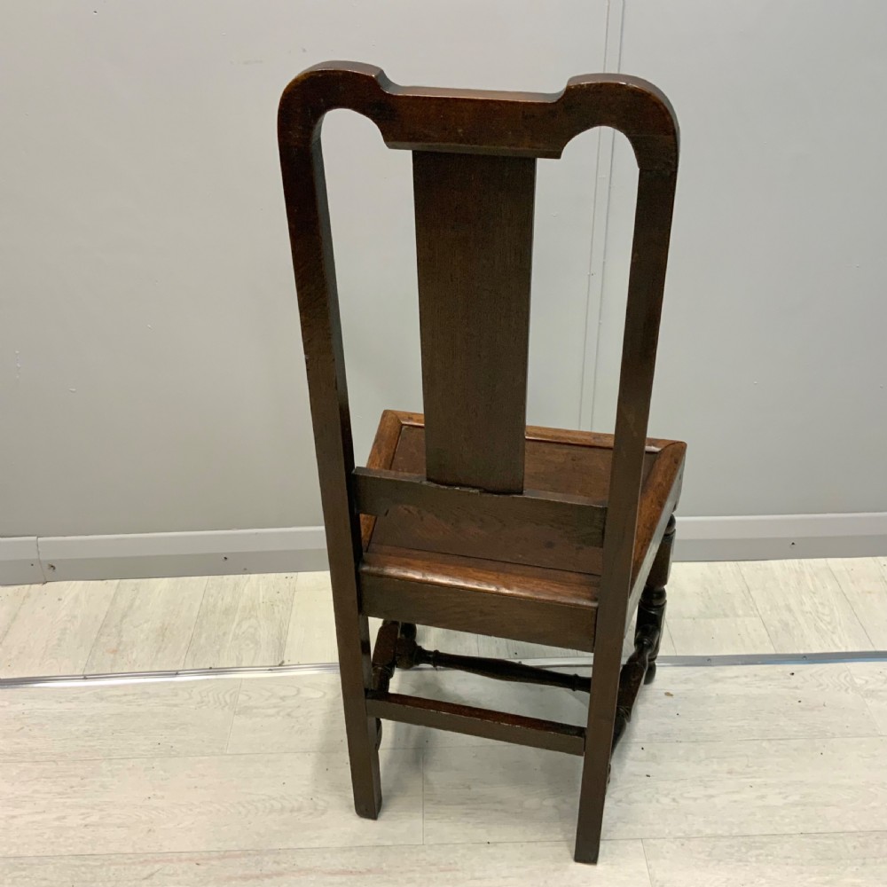 A late 17th-century dark oak back stool side chair featuring a solid wooden seat, central back splat, and turned front legs with stretchers. View VI
